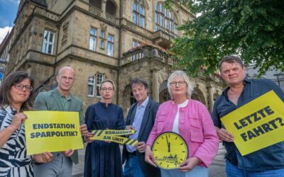 Sechs Personen protestieren mit gelben Schildern „Endstation Sparpolitik“, „Kommunen am Limit“ und „Letzte Fahrt?“ vor