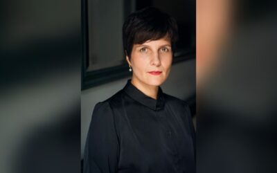 Anne Stern, eine Frau mit kurzen dunklen Haaren, schwarzer Bluse und Perlenohrring, blickt in die Kamera