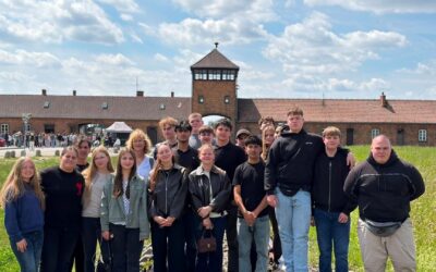 Gruppe junger Menschen und Erwachsene vor dem Backsteintorhaus des ehemaligen Konzentrationslagers Auschwitz-Birkenau