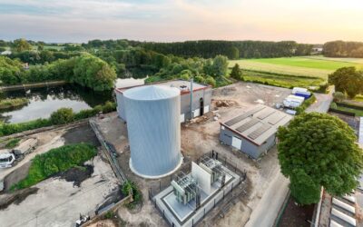 Luftbild einer Energieanlage mit Umspanntechnik, großem Silo, Gebäuden, einem See und grünen Feldern