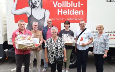 Ingrid Krause gratuliert sechs Blutspendern mit Geschenkkörben und Gutscheinen vor einem Blutspendefahrzeug