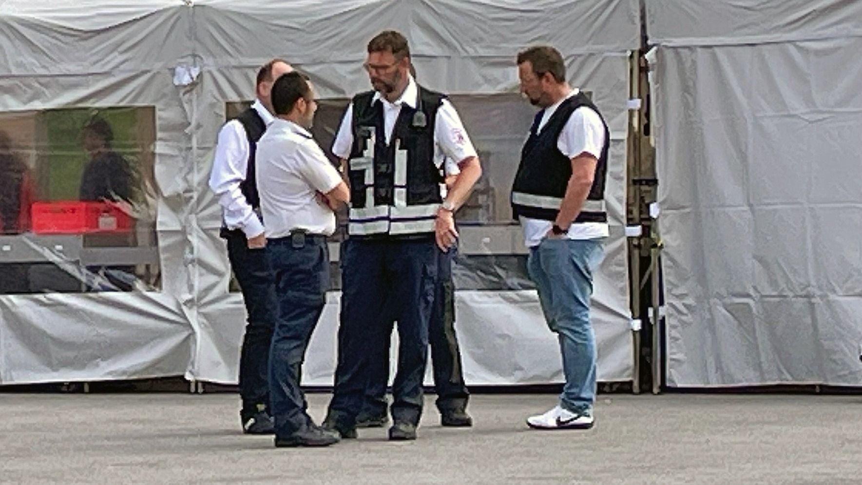 Drei Männer in Einsatzkleidung stehen vor einem weißen Zelt und unterhalten sich während einer Übung