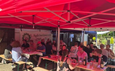 Sommerfest des 1. Apfelweinvereins OWL e.V. mit vielen Gästen, die unter roten Zelten an Tischen sitzen