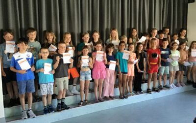 Eine Gruppe lächelnder Grundschulkinder der Grundschule Asemissen steht vor einem Vorhang und hält stolz ihre Urkunden