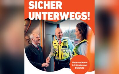 Drei lächelnde Personen in Uniformen und Warnwesten im Gespräch in einem Nahverkehrszug
