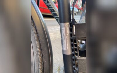 Nahaufnahme eines silbernen ADFC-Aufklebers "RAD IST CODIERT" mit Code auf schwarzem Fahrradrahmen