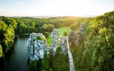 Die Externsteine, markante Felsformationen, umgeben von einem See und dichtem Wald im goldenen Abendlicht