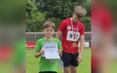 Zwei Jungen auf einem Podest, der linke mit grünem Shirt hält eine Urkunde und Silbermedaille, der rechte im roten