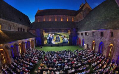 Zahlreiche Zuschauer sehen Open-Air-Kino im erleuchteten Kreuzgarten des Klosters Alpirsbach bei Nacht