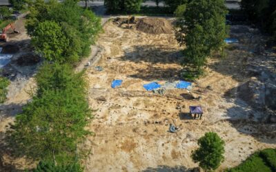 Luftaufnahme einer großen archäologischen Ausgrabungsstätte mit Baggern, Zelten und freigelegten Strukturen im Boden