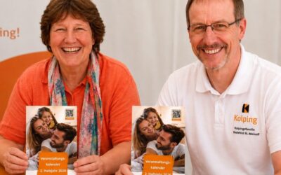 Eine lächelnde Frau und ein lächelnder Mann präsentieren jeweils einen Kolping-Veranstaltungskalender „2. Halbjahr 2026“
