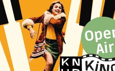 Lächelnde Frau in brauner Pelzjacke und grünem Minirock vor stilisierten Tasten, dazu Logos "Open Air" und "KNUP Kino