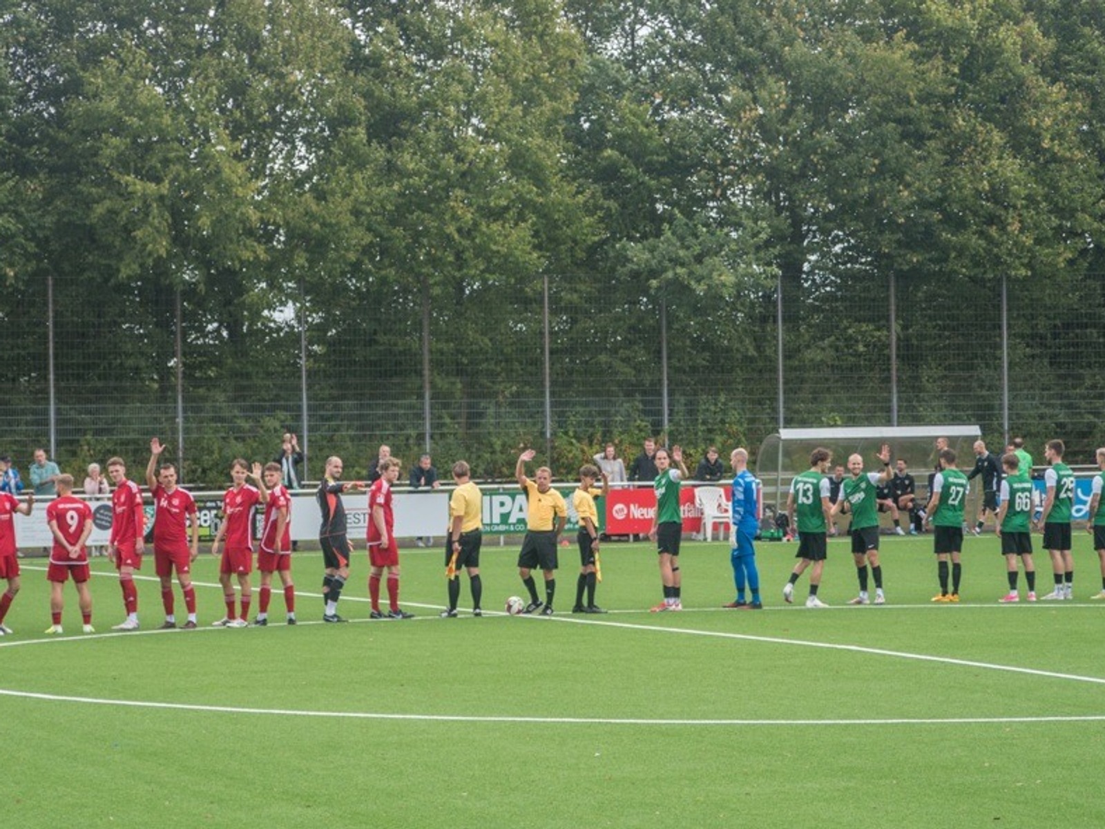 Spieler von TuS Lipperreihe (grün) und Dornberg (rot) grüßen sich mit Schiedsrichtern vor dem Fußballspiel auf dem Platz
