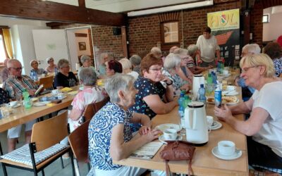 Senioren sitzen im Raum des Heimatvereins Leopoldshöhe an Tischen bei Kaffee und Kuchen zusammen und unterhalten sich