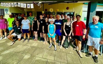 Gruppe von über 20 Personen in Sportkleidung steht vor einem Clubhaus mit Schleifchenturnier-Banner
