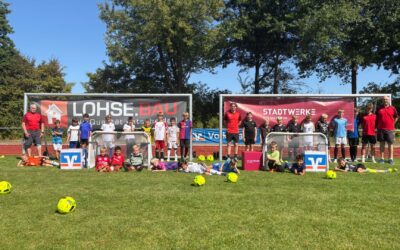 Gruppe Kinder und Erwachsene auf Fußballfeld beim Bad Salzufler Camp, teils liegend, mit Toren und Bällen