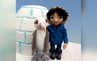 Albatros Albi und eine menschliche Figur in blauer Winterkleidung umarmen sich vor einem Iglu auf Schnee