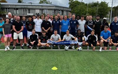 Große Gruppe von Personen posiert auf einem Kunstrasen-Sportplatz, einige halten ein blaues Banner "FÜR LEOPOLDSHÖHE