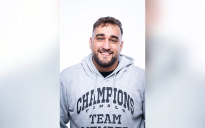 KARLITOZ lächelt in einem grauen Hoodie mit der Aufschrift "Champions Finals Team Member" direkt in die Kamera