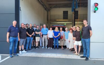 Mitglieder der SPD-Fraktion stehen vor der offenen Fahrzeughalle einer Feuerwache mit rotem Einsatzfahrzeug