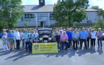 DAVC-Gruppe und Polizistin mit Oldtimer und gelbem Banner vor dem Gebäude der Bundespolizei mit Uhr
