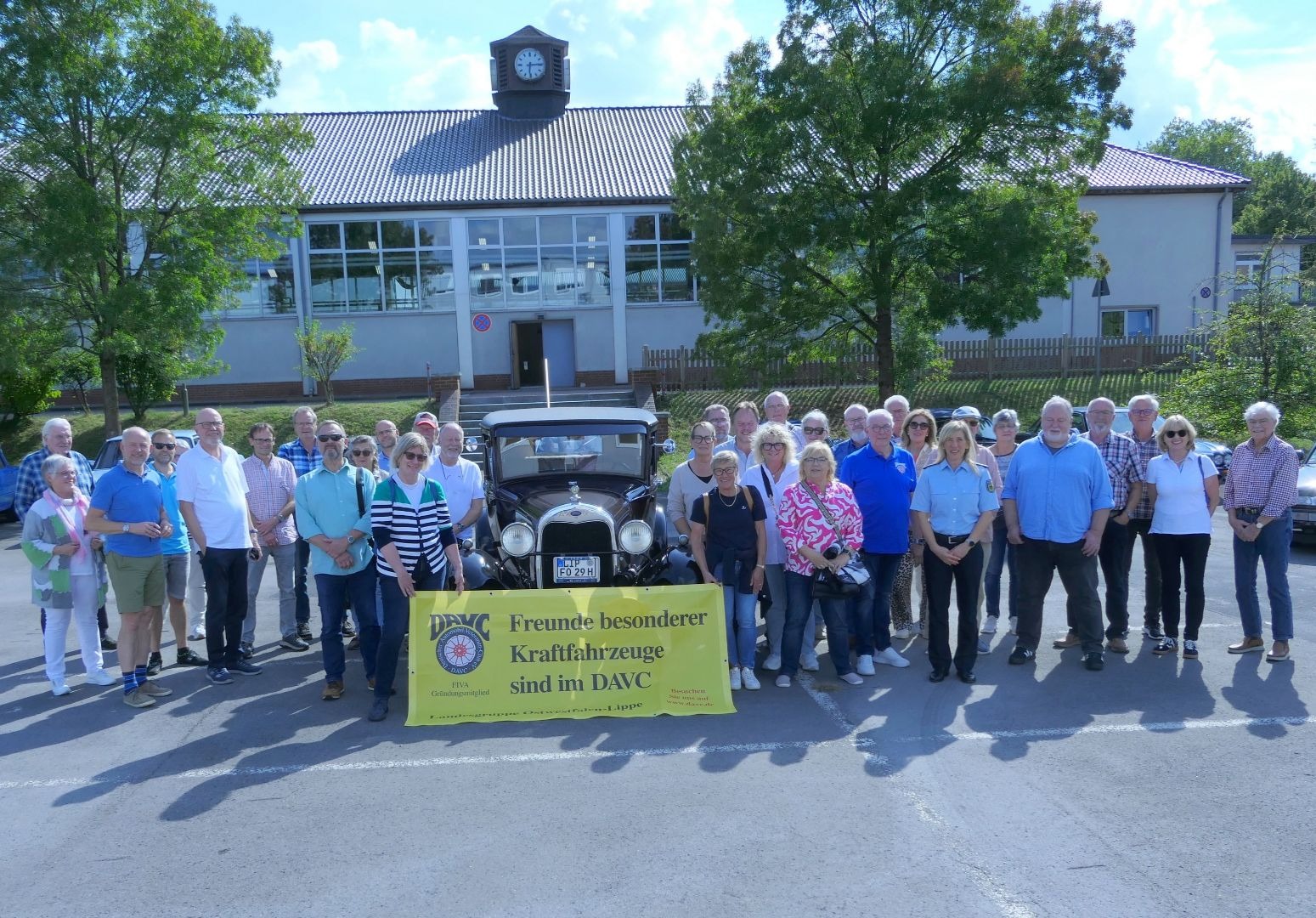 DAVC-Gruppe und Polizistin mit Oldtimer und gelbem Banner vor dem Gebäude der Bundespolizei mit Uhr
