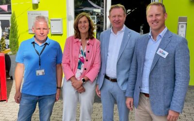 Vier Personen, drei Männer und eine Frau, lächeln vor dem Eingang der Kinderpsychiatrie Salzuflen