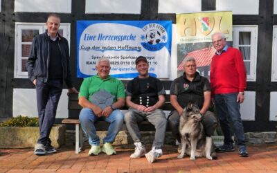 Fünf Männer und ein Hund vor einem Fachwerkhaus, mit Banners zum „Cup der guten Hoffnung“ und „Heimatverein