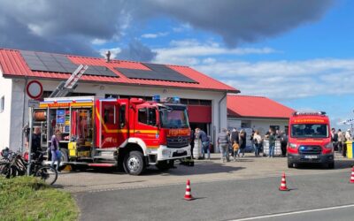 Zwei rote Feuerwehrautos vor einem Feuerwehrhaus mit Besuchern beim Tag der offenen Tür