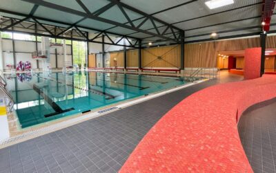Leeres Schwimmbecken im Lohfeld Bad mit Sprungturm, Startblöcken und einer geschwungenen roten Wand