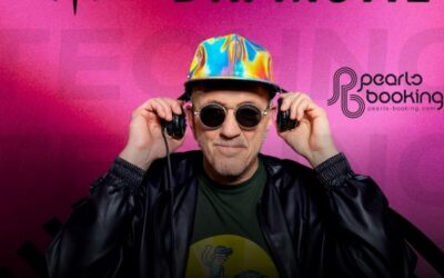 Dr. Motte mit Sonnenbrille und bunter Kappe hält Kopfhörer an die Ohren und lächelt leicht