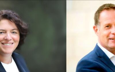 Die lächelnde Frau Vieregge mit dunklen Locken und der lächelnde Mann Hansen mit kurzem hellem Haar schauen frontal