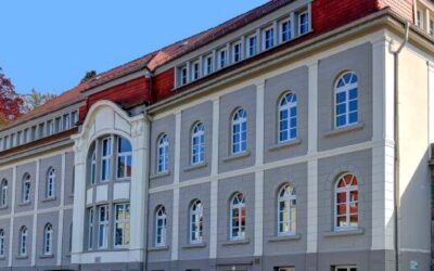 Großes graues Gebäude des Gesundheitszentrums Oerlinghausen mit rotem Mansarddach und vielen Bogenfenstern