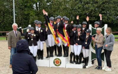Reiterinnen als Lippische Dressur Meister Mannschaft 2026 auf einem Siegerpodest, mit Medaillen und Bändern, jubelnd