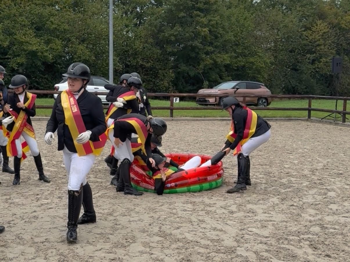 Reiter mit Schärpen schubsen eine Person bei der Schuckenbaumer Outdoors Meisterehrung in ein Planschbecken