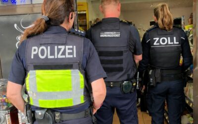 Drei Beamte von Polizei, Kommunalem Ordnungsdienst und Zoll betreten einen Kiosk