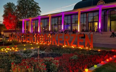 Abendliche Szene im Kurpark mit beleuchtetem Gebäude, dem Schriftzug NACHT DER 100000 KERZEN, vielen Lichtern und