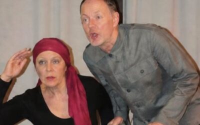 Zwei Darsteller, eine Frau mit rotem Kopftuch und ein Mann an einer Holzleiter, blicken rufend nach vorne