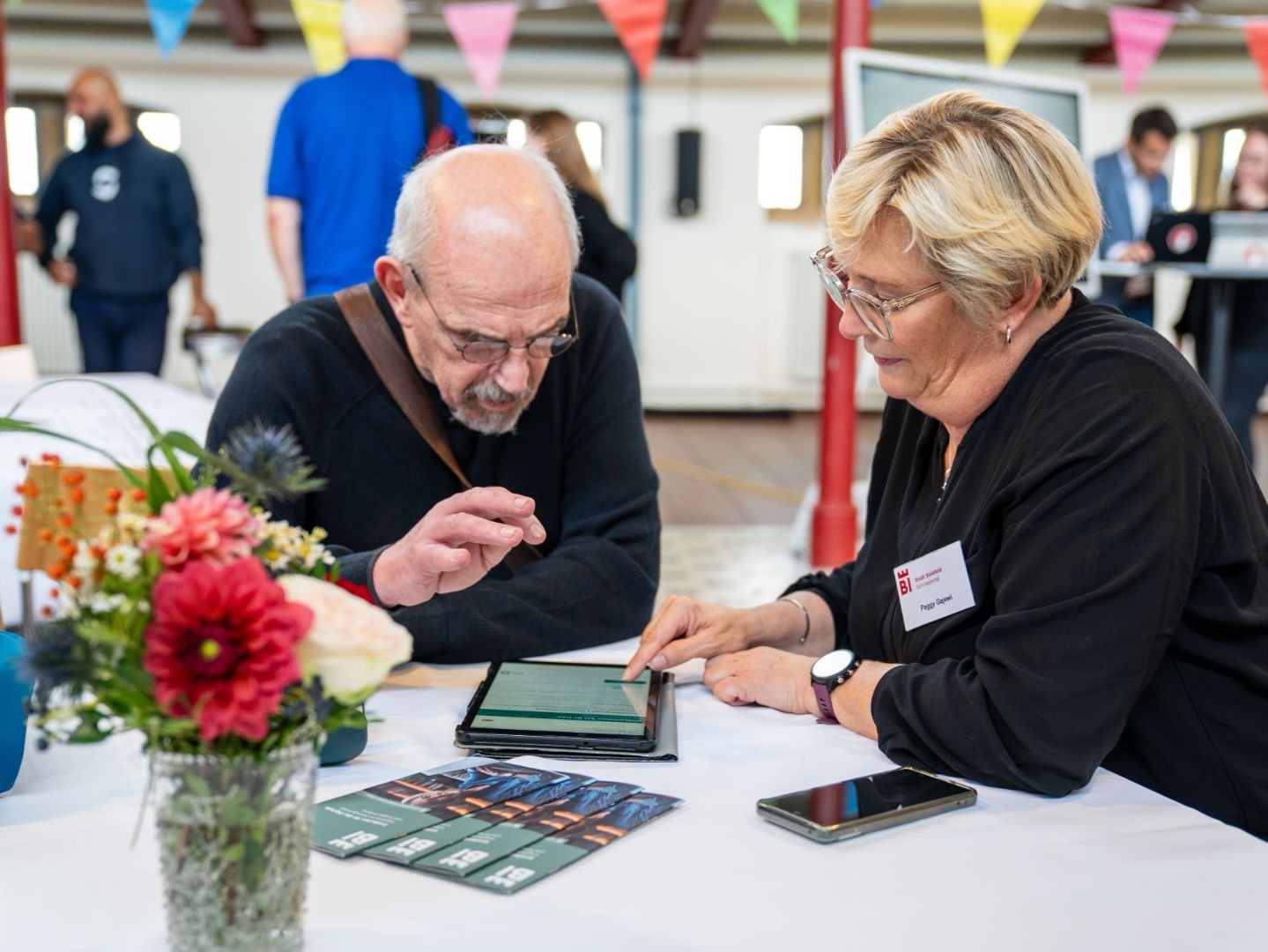 Peggy Gajewi vom Stadt Bielefeld Serviceportal und ein Mann bedienen ein Tablet