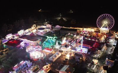 Luftaufnahme des hell beleuchteten Wilbaser Marktes bei Nacht mit Riesenrad, Fahrgeschäften und vielen Besuchern